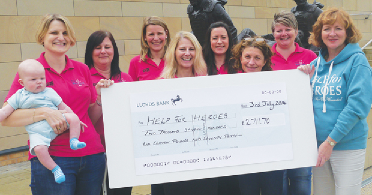 Members of the Military WAGS Choir handing over a cheque to Help For Heroes